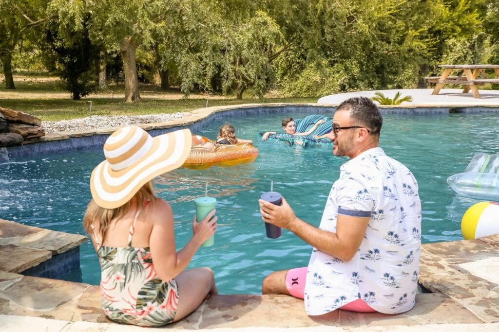 Man and woman toasting drinks by the pool