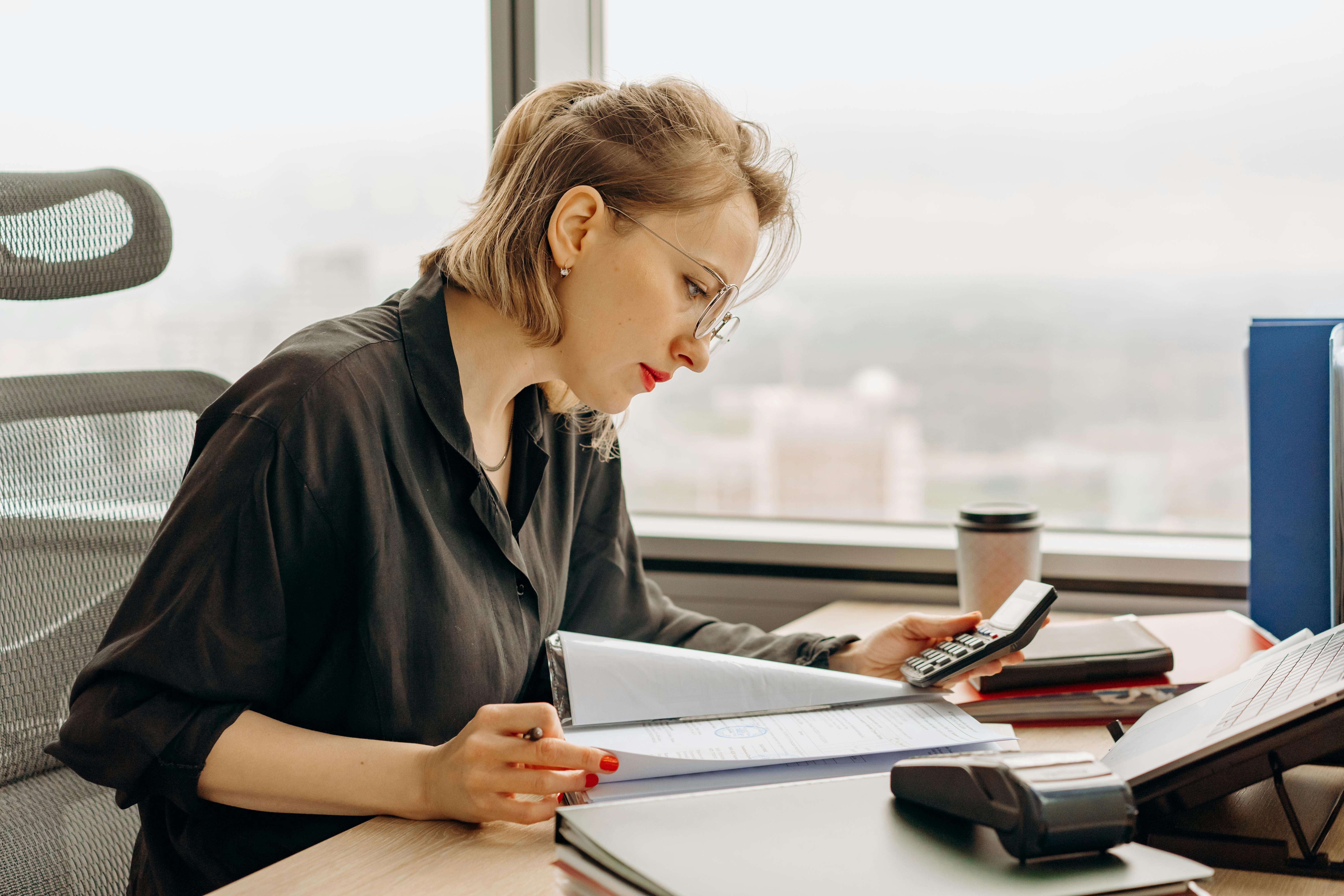 8297044 Woman accountant calculating financial documents at office desk.