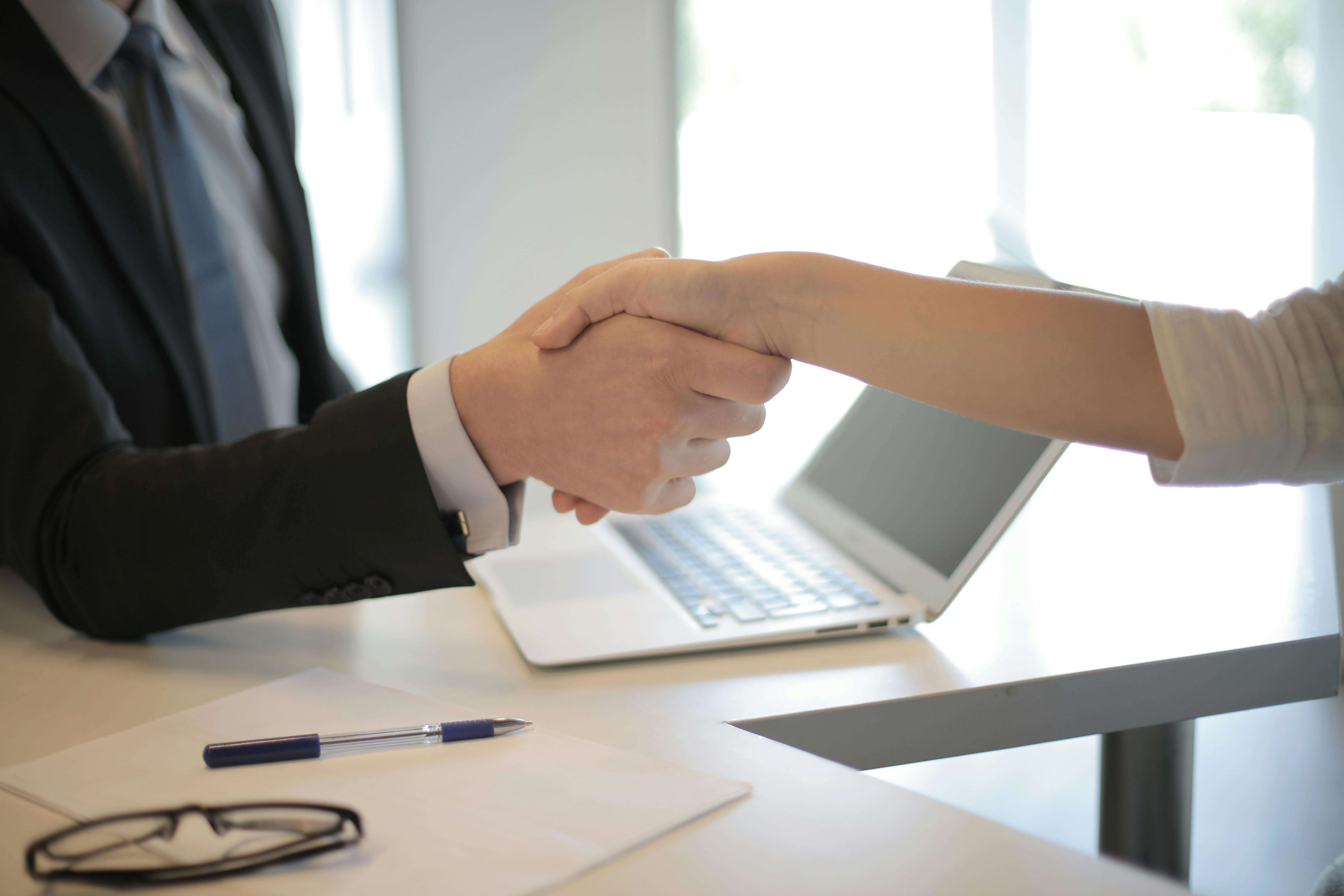 3760069 Close-up of a professional handshake over a laptop during a business meeting in an office.