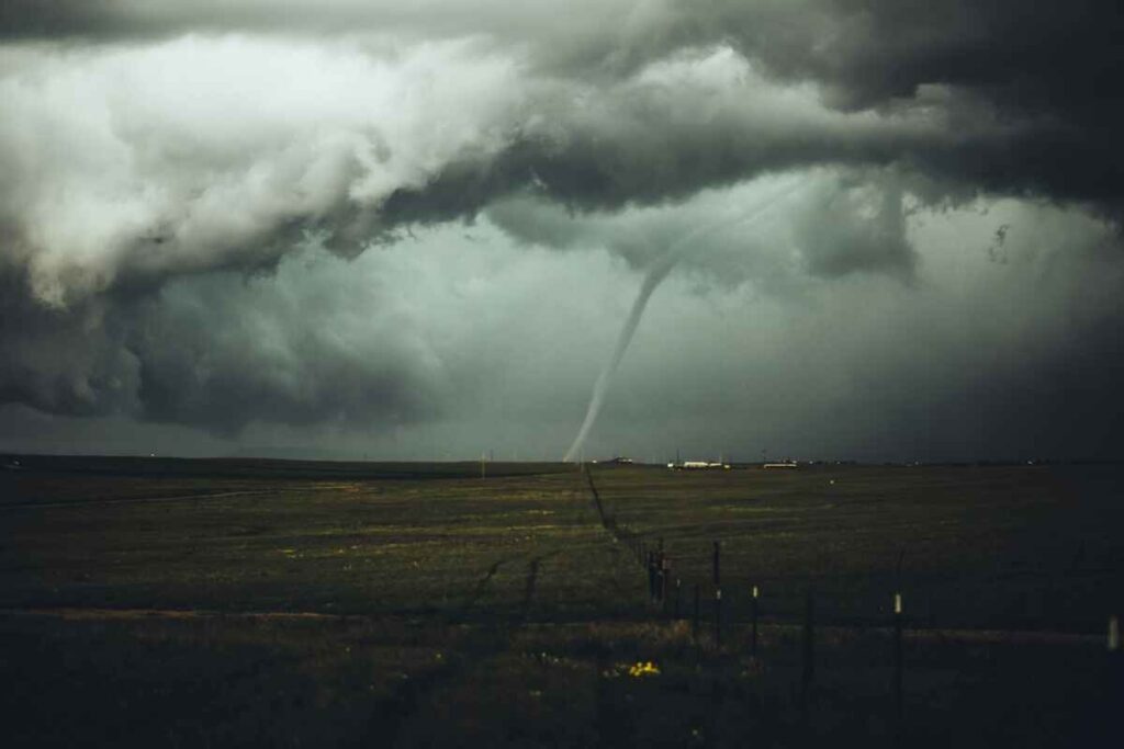 Tornado over open field under dark storm clouds