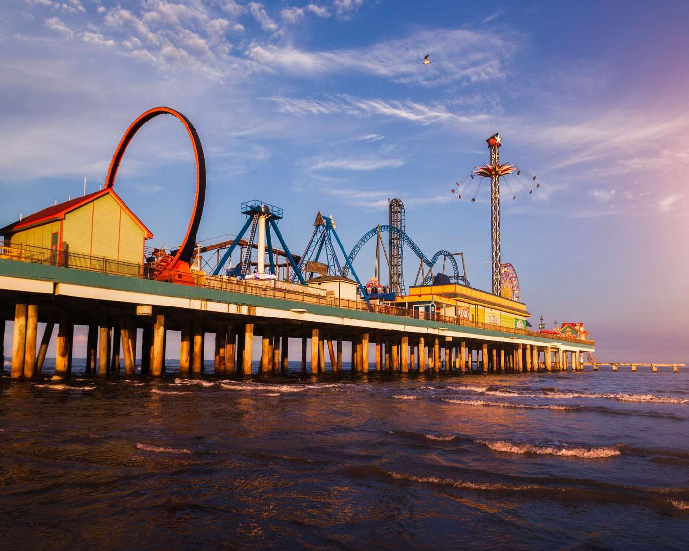 2386404 Vibrant sunset over Galveston's iconic amusement pier with thrilling rides and ocean waves.