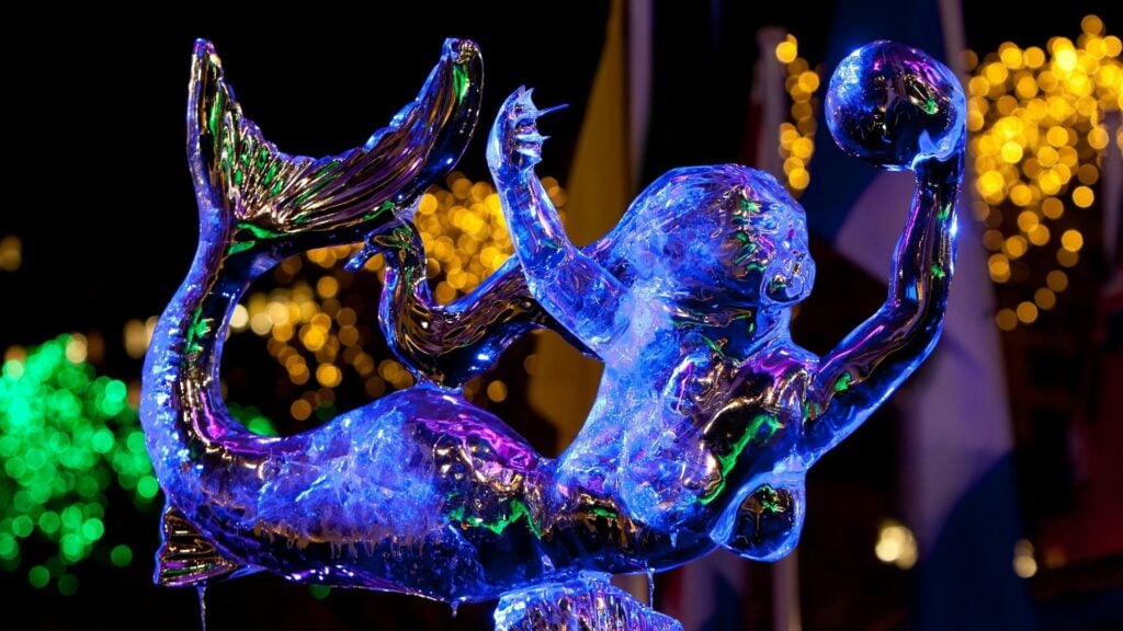 Lit ice sculpture of a mermaid surrounded by holiday lights